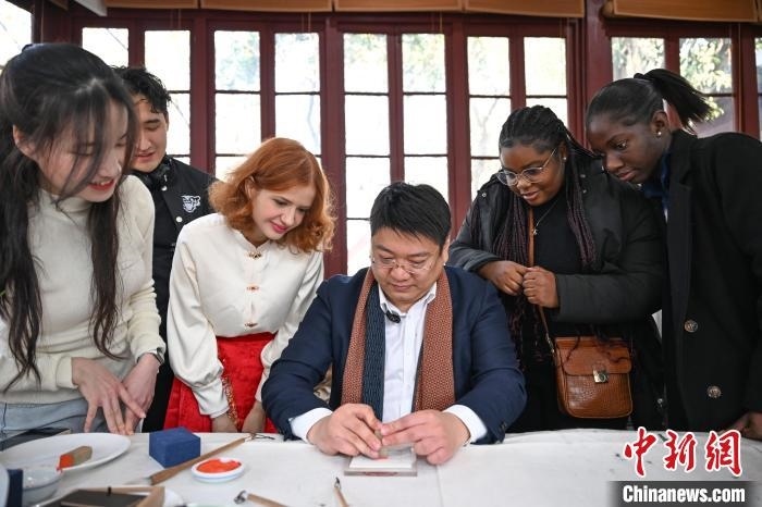 1月20日，篆刻家王臻向外籍留學(xué)生展示篆刻印章。當(dāng)日，來自巴西、馬來西亞、加納、哈薩克斯坦的外籍留學(xué)生在浙江杭州西泠印社體驗(yàn)福貼、春聯(lián)和篆刻，感受古老的中國傳統(tǒng)文化。中新社記者 王剛 攝