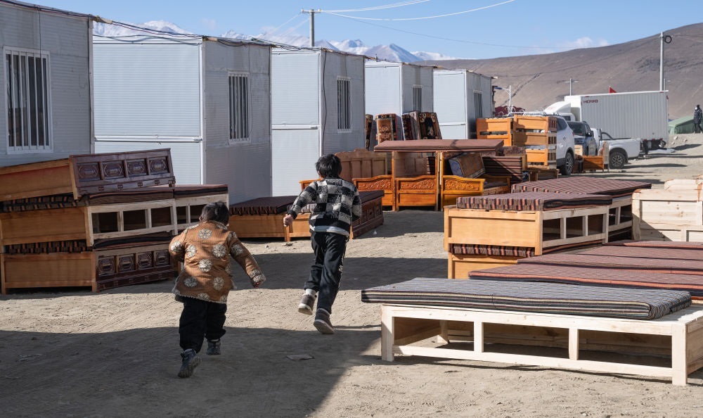 2025年1月13日，在定日縣嘎旦村，兩個孩子在剛運來的兩排藏床間奔跑。新華社記者丁增尼達(dá) 攝