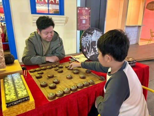 柯秋楓與市民下椰雕象棋。人民網(wǎng) 陳葉欣攝