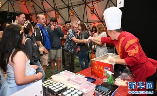 圖為游客在燈節(jié)現(xiàn)場購買小吃。（圖片由奧克蘭中國文化中心提供）
