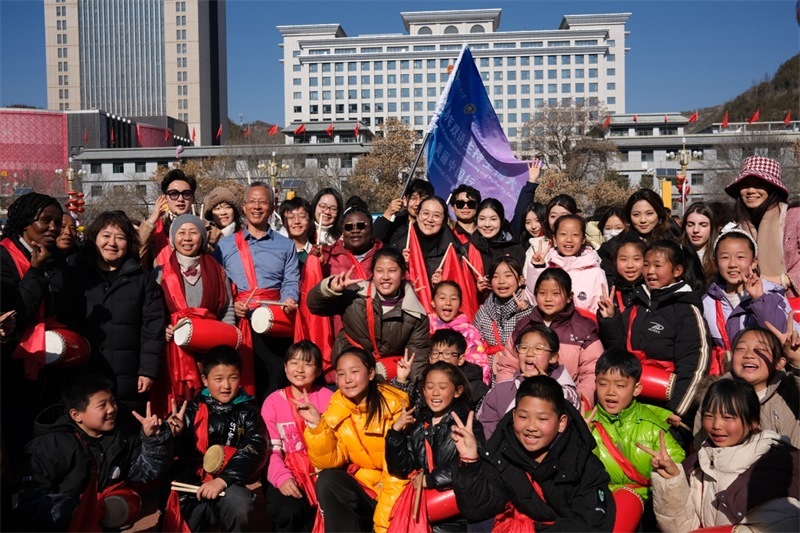 中外青年學(xué)子在安塞文化廣場觀看陜北腰鼓和大秧歌表演后合影留念，大家踏著鼓點(diǎn)共舞，翻飛的紅綢與躍動的身影交織，在黃土地廣場上繪出一幅生動的陜北民俗互動畫卷