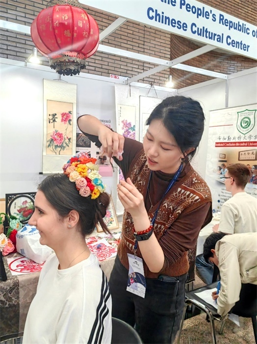 展覽正值羅馬尼亞迎春花節(jié)，國(guó)際中文教師志愿者潘婧穎向游客們介紹了國(guó)家非物質(zhì)文化遺產(chǎn)——福建泉州的簪花文化。布加勒斯特大學(xué)孔子學(xué)院供圖。