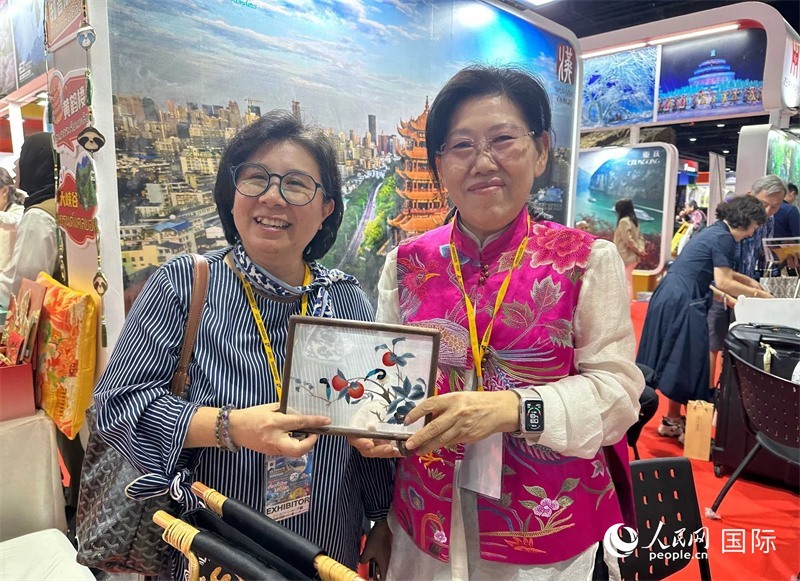中國“大冶刺繡”傳承人劉小紅（右）參加泰國國際旅游展，向觀眾介紹中國非遺刺繡針法。人民網(wǎng)記者 簡承淵攝