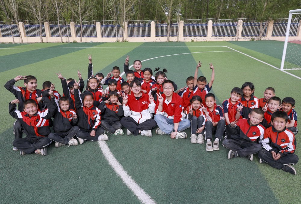4月23日，在新疆克州阿圖什市哈拉峻鄉(xiāng)謝依特小學，支教教師王俊文（中左）、李軻凡（中右）和學生在一起。
