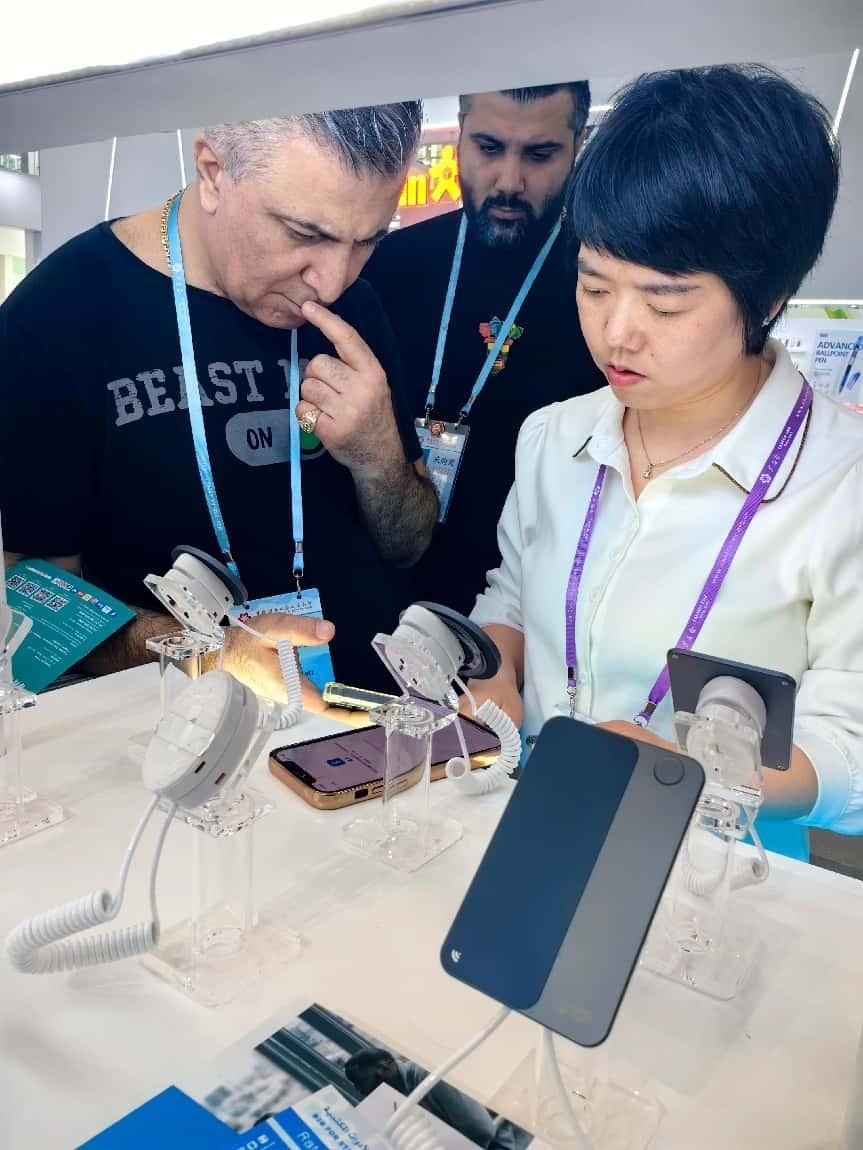 展臺工作人員向外商展示“AI TOP翻譯終端”。圖片來源：受訪者提供